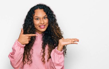 Kıvırcık saçlı, sıradan bir kazak giyen genç İspanyol kadın kameraya hayret ediyor ve gülümsüyor.. 