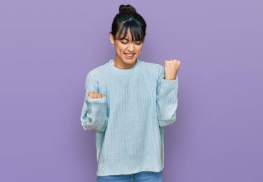 Gündelik giysiler giyen genç İspanyol kadın şaşkınlık ve şaşkınlık içinde kollarını kaldırarak ve gözlerini kapayarak başarıyı kutluyor. Kazanan konsept. 