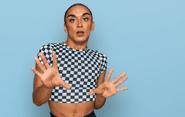 Makyaj yapan İspanyol transseksüel adam ve modern kıyafetler giyen, korku ifadesinden korkan ve dehşete düşmüş uzun saçlı adam. El hareketlerini durdur, şok içinde bağır. panik konsepti. 