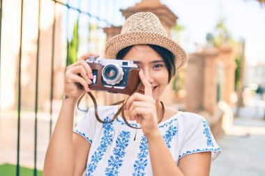 Tatildeki genç Latin turist kız şehirde klasik kamera kullanarak mutlu mesut gülümsüyor..