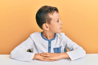 Kafkasyalı sevimli bir çocuk, günlük giysiler giymiş, yan tarafa bakıyor, rahat profil pozu veriyor, kendine güvenen bir gülümsemesi var.. 