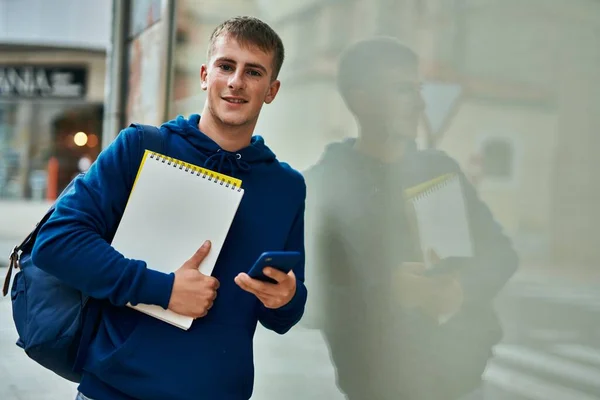 Mladý Blond Student Pomocí Smartphone Držení Notebook Univerzitě — Stock fotografie