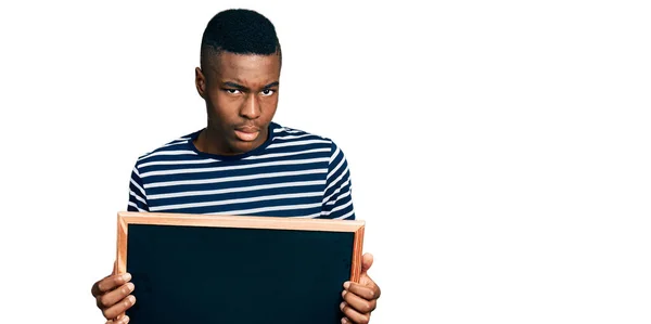 若いアフリカ系アメリカ人の男性は 問題のために動揺を眉をひそめて 懐疑的で緊張した黒板を持っています 否定的な人 — ストック写真