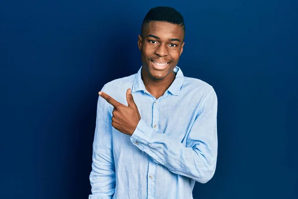若いアフリカ系アメリカ人の男性は 笑顔で陽気な服を着て 手と指で顔に幸せと自然な表情で側面まで指しています — ストック写真