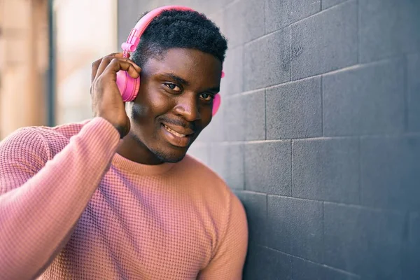 年轻的非洲裔美国人在城里用耳机开心地微笑着 — 图库照片