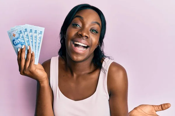 Young African American Woman Holding Thai Baht Banknotes Celebrating Achievement — Foto de Stock