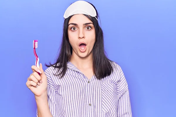 Young Beautiful Girl Wearing Sleep Mask Holding Toothbrush Scared Amazed — Stock Photo, Image