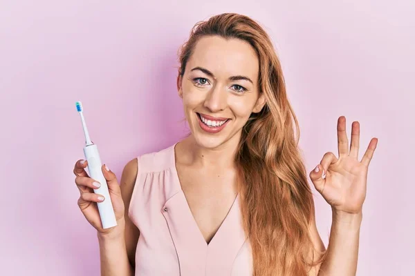 Mulher Caucasiana Jovem Segurando Escova Dentes Elétrica Fazendo Sinal Com — Fotografia de Stock