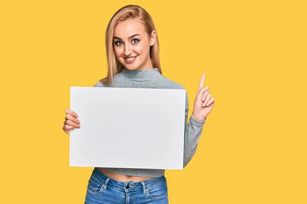 Hermosa Mujer Caucásica Sosteniendo Una Pancarta Vacía Blanco Sorprendida Con —  Fotos de Stock