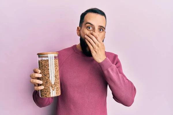 Joven Con Barba Sosteniendo Tarro Cereales Integrales Sanos Cubriendo Boca — Foto de Stock