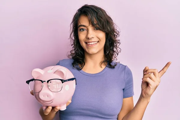 Young Hispanic Woman Holding Piggy Bank Glasses Smiling Happy Pointing — Stock Photo, Image