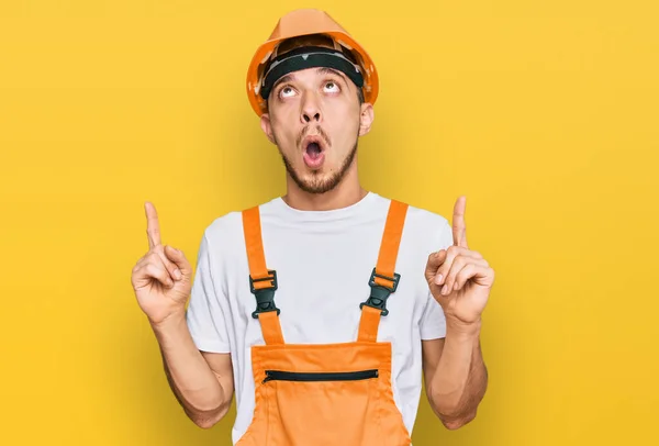 Hispanic Young Man Wearing Handyman Uniform Safety Hardhat Amazed Surprised — 图库照片