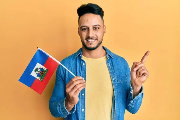 Joven Árabe Sosteniendo Bandera Haiti Sonriendo Feliz Señalando Con Mano —  Fotos de Stock