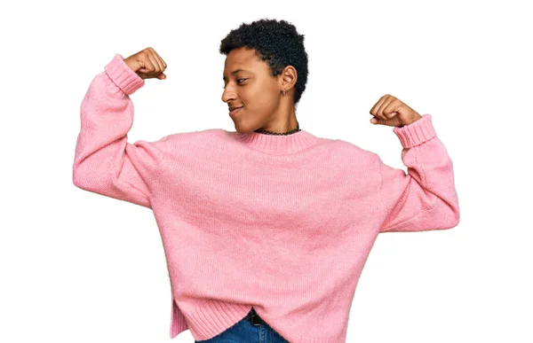 アフリカ系アメリカ人の若い女性が腕の筋肉を示すカジュアルな服を着て誇らしげに笑っている フィットネスのコンセプト — ストック写真