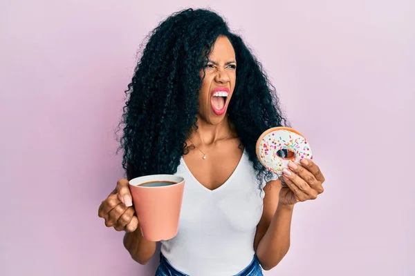 Mulher Afro Americana Meia Idade Comendo Donuts Bebendo Café Zangado — Fotografia de Stock