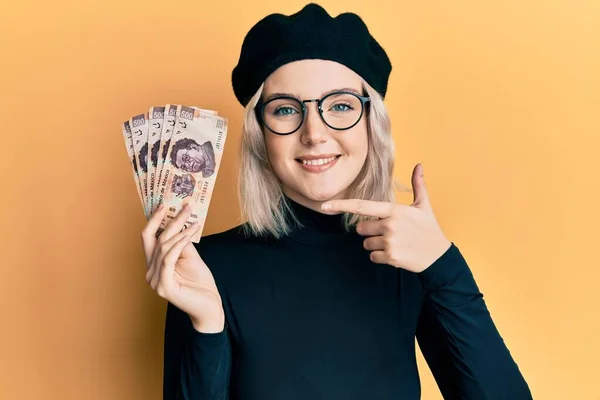 Ung Blond Flicka Håller Mexikanska Pesos Ler Glad Pekar Med — Stockfoto