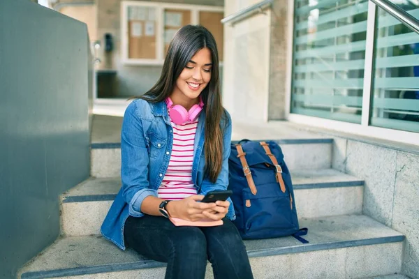 若いですヒスパニック系の学生の女の子笑顔幸せな使用スマートフォンで大学 — ストック写真