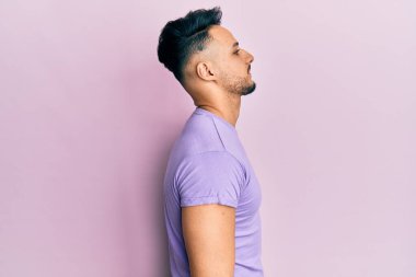 Gündelik giysiler giyen genç bir Arap, rahat bir görünüm takınıyor, kendine güvenen bir gülümsemeyle doğal bir yüz ifadesi sergiliyor.. 