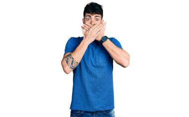 Gündelik tişört giyen genç İspanyol adam yanlışlıkla elleriyle ağzını kapatırken şok oldu. gizli kavram. 