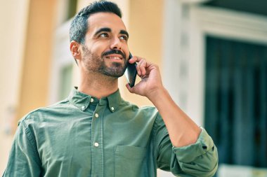 Genç İspanyol adam gülümsüyor. Şehirdeki akıllı telefondan konuşuyor..