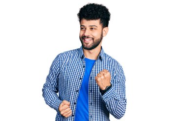 Sakallı, sıradan gömlekli genç bir Arap, kolları havada ve gözleri kapalı bir şekilde başarıyı kutluyor ve şaşırıyor. 