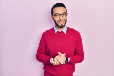 Sakallı, iş gömleği giyen, gözlüklü, elleri birarada gezen ve gülümseyen İspanyol bir adam. Başarı ve iyimserlik 