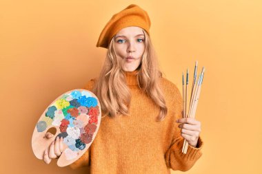 Güzel beyaz kız elinde boya fırçası ve ressam paleti ile balık suratlı ve şaşı gözlü, çılgın ve komik.. 