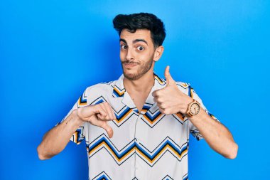 Latin asıllı genç bir adam günlük kıyafetler giyip baş parmak kaldırıyor, anlaşmazlık ve uzlaşma ifadesi. çılgın çatışma 