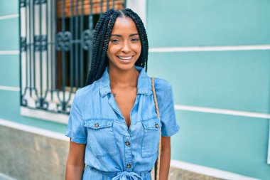 Genç Afrikalı Amerikalı kadın gülümseyerek şehirde mutlu mesut yürüyor..