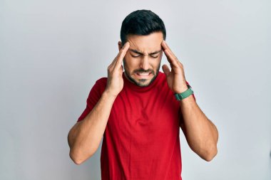 Stres yüzünden başı ağrıyan Latin kökenli genç bir adam günlük kıyafetler giyiyor. migren ağrısı. 