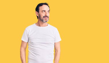 Orta yaşlı yakışıklı bir adam, sıradan bir tişört giyiyor, gülümsüyor, yan tarafa bakıyor ve düşünüyor.. 