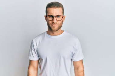 Gündelik kıyafetler giyen, gözlüklü, şüpheci ve gergin genç beyaz bir adam sorun yüzünden üzgün. negatif kişi. 