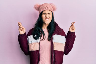 Kışlık yün kazak giyen genç İspanyol kadın ve umut ve gözleri kapalı gülümseyerek el hareketi yapan parmaklar çapraz. Şans ve batıl inançlar. 