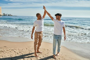 Genç eşcinsel çift gülümsüyor Kumsalda dans ederken mutlu.