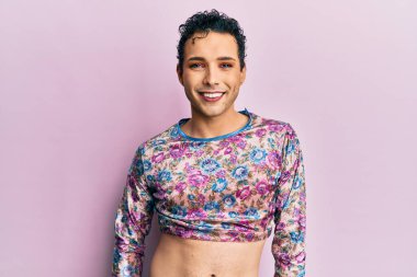 Makyaj yapan yakışıklı bir adam. Yüzünde mutlu ve havalı bir gülümseme olan moda kıyafetleri giyiyor. şanslı kişi. 