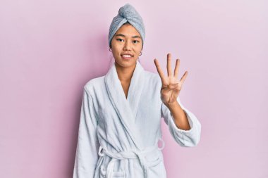 Duş havlusu şapkası ve bornoz takan genç Çinli kadın dört numarayı gösterip işaret ederken kendinden emin ve mutlu gülümsüyor.. 