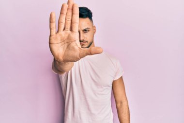 Gündelik giysiler giyen genç bir Arap avucuyla şarkı söylemeyi kesiyor. Yüzünde olumsuz ve ciddi bir jest olan uyarı ifadesi. 