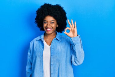 Gündelik kıyafetler giyen, gülümseyen genç Afro-Amerikalı kadın el ve parmaklarıyla 