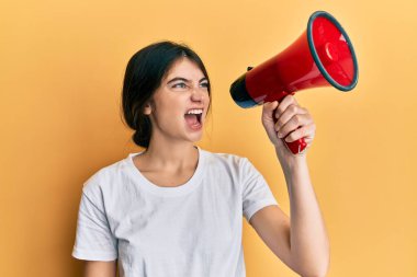 Sarı arka planda megafonu olan genç ve güzel bir kadın akıllı bir ifadeyle büyük bir elbisenin içinden bağırıyor.