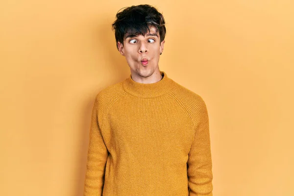 唇で魚の顔を作るカジュアルな黄色のセーターを着てハンサムなヒップスター若い男 狂気とコミカルなジェスチャー 面白い表現 — ストック写真