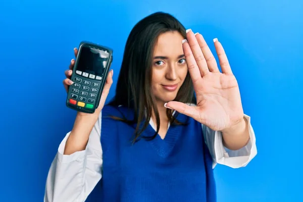Młoda Latynoska Dziewczyna Trzyma Dataphone Otwartą Ręką Robi Znak Stop — Zdjęcie stockowe