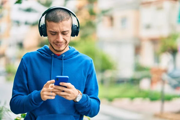 Jonge Spaanse Man Glimlacht Gelukkig Met Behulp Van Smartphone Koptelefoon — Stockfoto