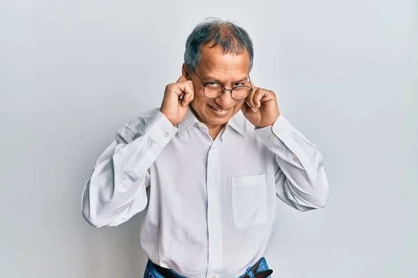 中年印度男人穿着休闲装 戴着眼镜 用手指捂住耳朵 对嘈杂的音乐感到恼怒 聋人概念 — 图库照片