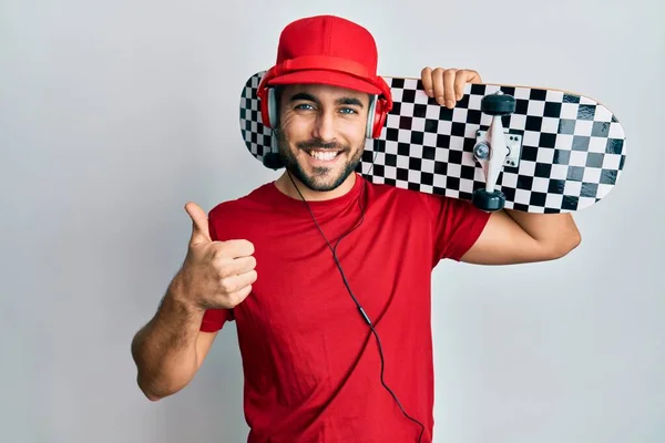 Jovem Hispânico Usando Fones Ouvido Segurando Skate Sorrindo Feliz Positivo — Fotografia de Stock