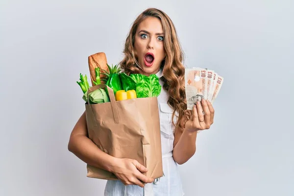 Young Blonde Girl Holding Paper Bag Groceries Pounds Afraid Shocked — Stock Photo, Image