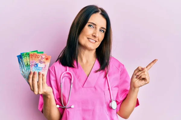Médico Morena Meia Idade Segurando Francos Suíços Sorrindo Feliz Apontando — Fotografia de Stock