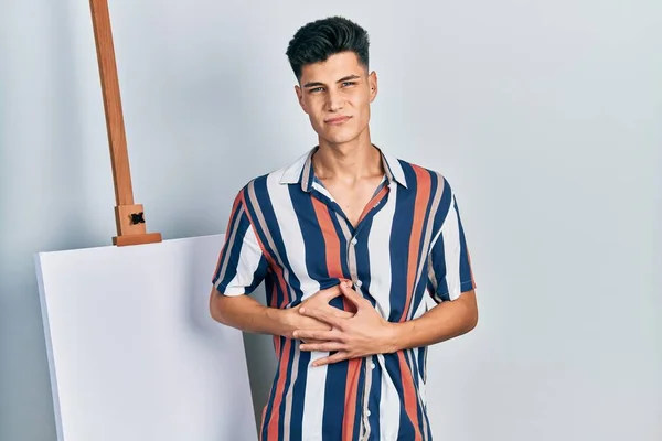 Young Hispanic Man Standing Close Empty Canvas Hand Stomach Because — 스톡 사진