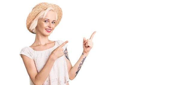 Młoda Blondynka Tatuażem Letnim Kapeluszu Uśmiechnięta Patrząca Kamerę Dwoma Rękami — Zdjęcie stockowe