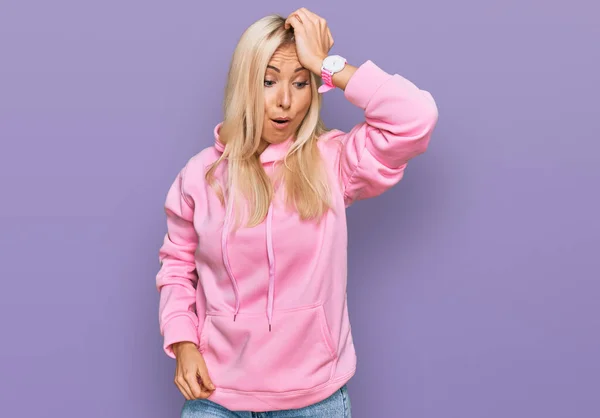 Ung Blond Kvinna Bär Casual Sweatshirt Överraskad Med Handen Huvudet — Stockfoto