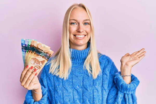 Joven Rubia Sosteniendo Dólares Canadienses Sonriendo Alegre Presentando Señalando Con — Foto de Stock